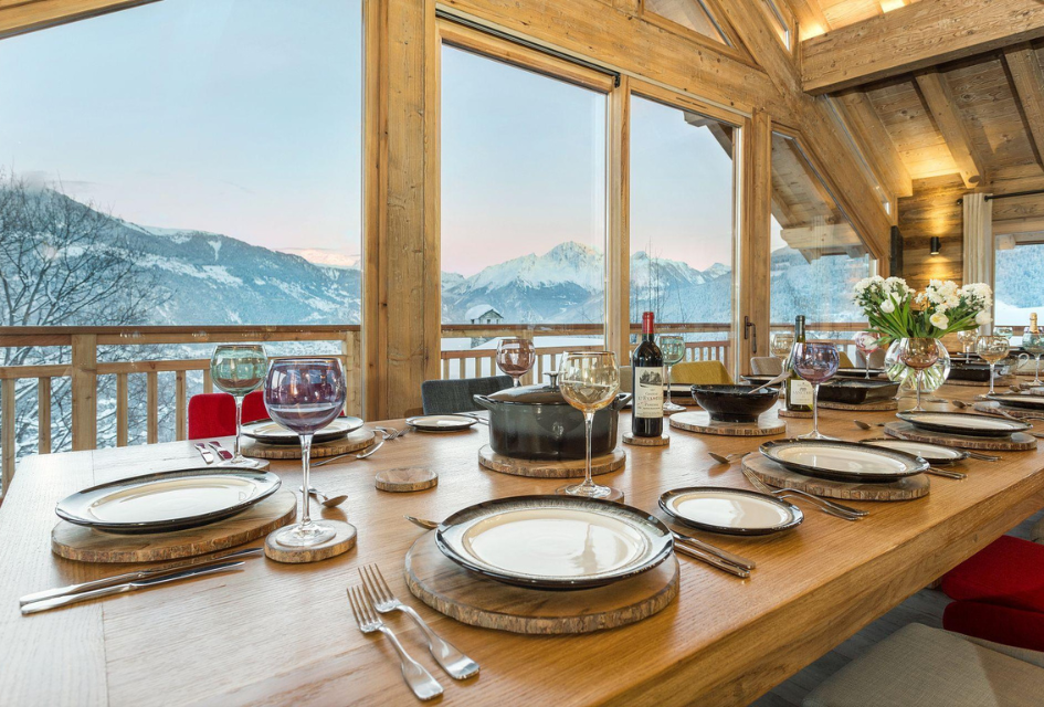 Laid dining table of Chalet Iona, one of the top catered ski chalets in the French Alps. Views out on a mountain sunset in Méribel.