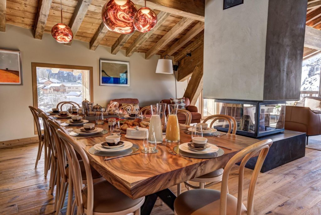 Interior of Chalet Constantia. The wood dining table is complete with breakfast of pastries and juices on a catered ski chalet holiday in France.