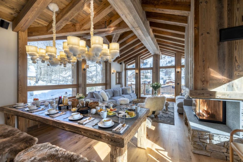 Chalet 1855 is one of the best luxury self catered ski chalets in France, not just Val d'Isère! Its open-plan living-dining area can be seen in this photo, with a fireplace to the right and snowy views outside.