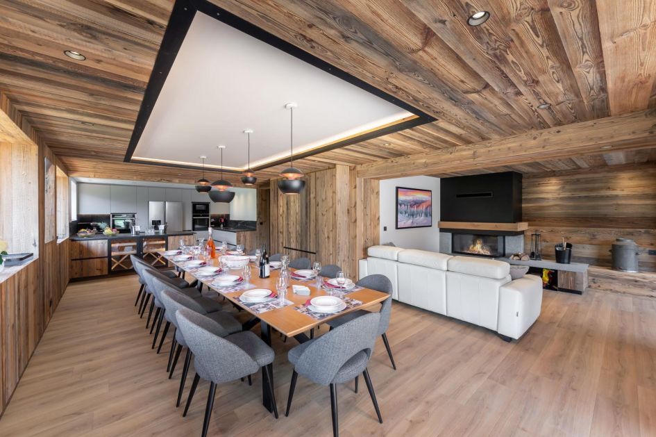 Chalet Carriaz is one of the best luxury self catered ski chalets in France for larger groups of 14. The dining table, pictured in the open-plan living area, can seat the whole group together amongst modern alpine decor.