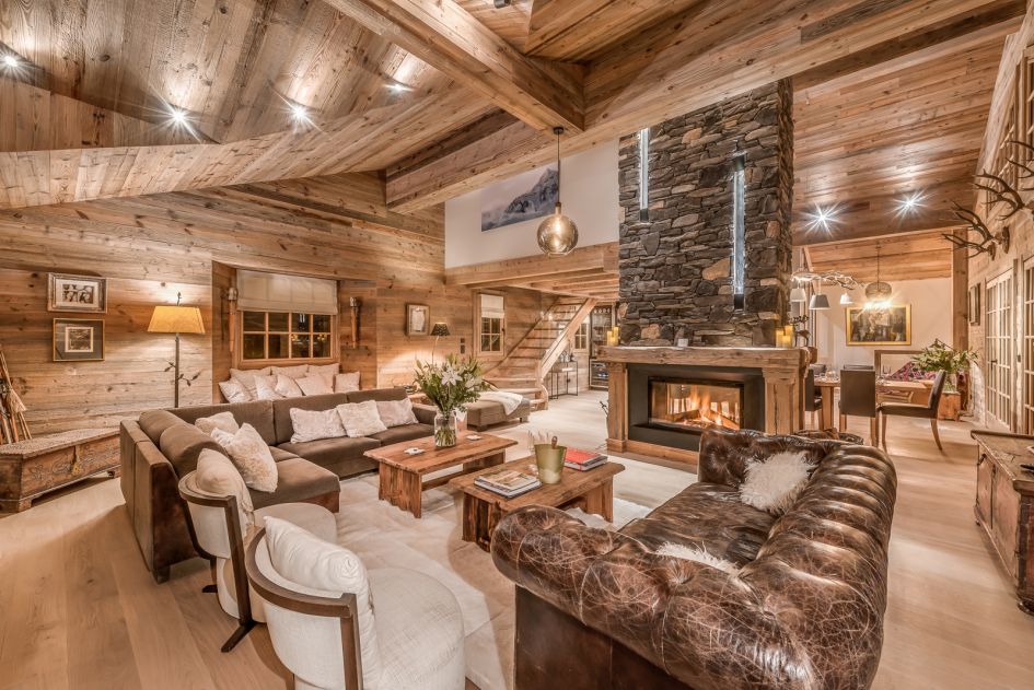 Spacious living room with plush sofas and crackling fireplace inside luxury chalet La Namaste in Courchevel 1850.