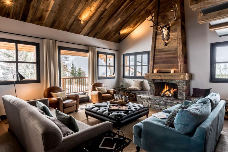 As one of the top luxury chalets in Méribel, Chalet Tomkins' elegant living area features high ceilings, a roaring wood fireplace (at the back) and a mix of comfortable and leather sofas huddled around the middle.