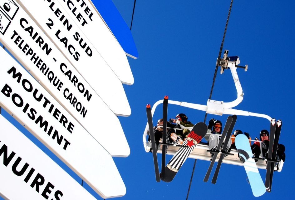 5 people riding a lift in Val Thorens, with a piste sign in the foreground.