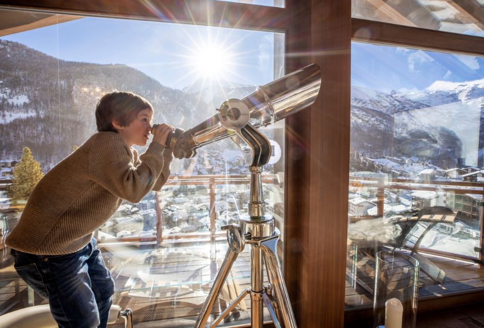 Young boy peeking through a telescope in Chalet Zermatt Peak.