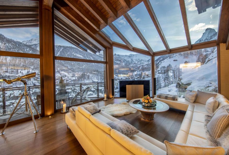 Chalet Zermatt Peak's expansive living area with full height glass walls and ceilings and Matterhorn views, with a telescope for stargazing in the Alps