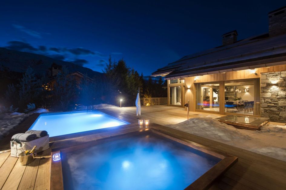 The immense view of Chalet Alpaca at night, lit up and with exceptional terrace wellness facilities such as the outdoor pool and hot tub - one of the best luxury chalets in Méribel!