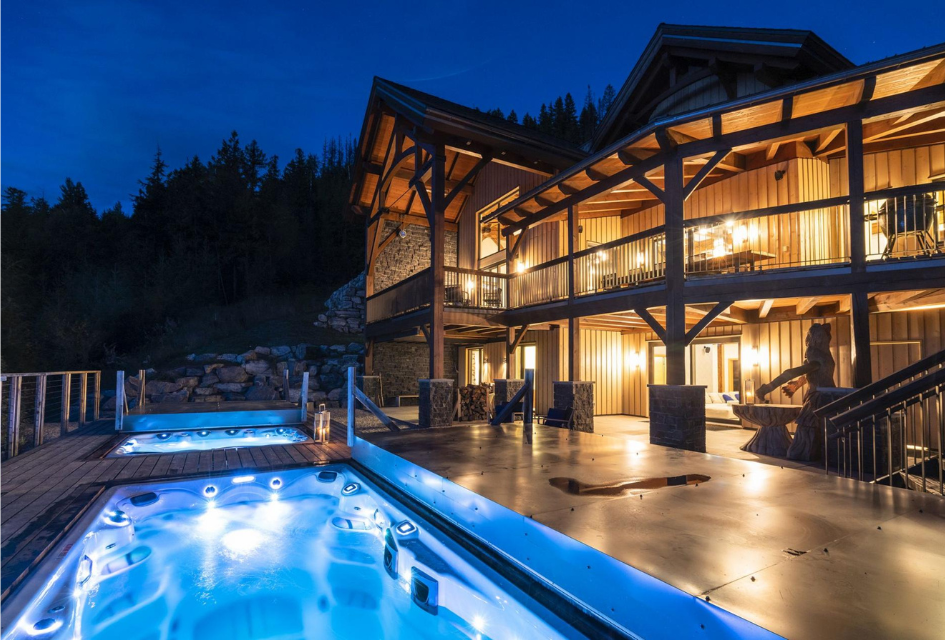 Exterior at night of Flying Moose Chalet in Revelstoke, showcasing outdoor swim-spa and hot tub.