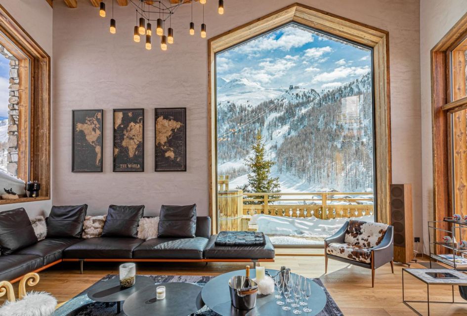 Living room of Chalet Les Ours, with tall windows showing the well-designed room in light, ready to welcome you to your luxury corporate ski chalet holiday.