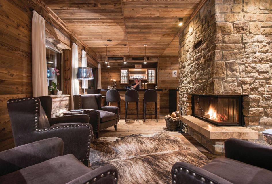 One of the living areas of Chalet Eden Rock, with a crackling fireplace, bar, and bartender pulling a pint, ideal for a luxury corporate ski holiday.