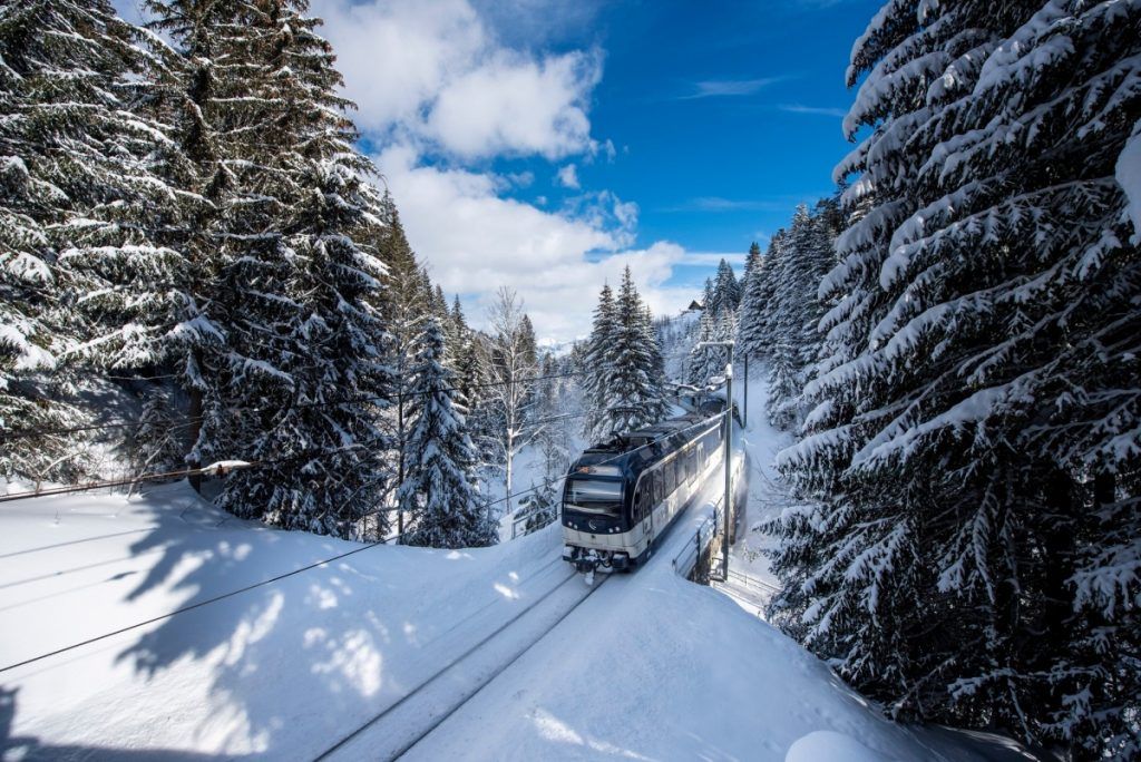 Train heading through snow covered trees on the way to Gstaad, Switzerland. 