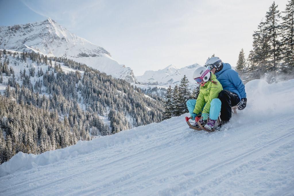 Two people enjoy sledding in Gstaad, proving that luxury ski holidays in Gstaad are suited to both skiers and non-skiers!