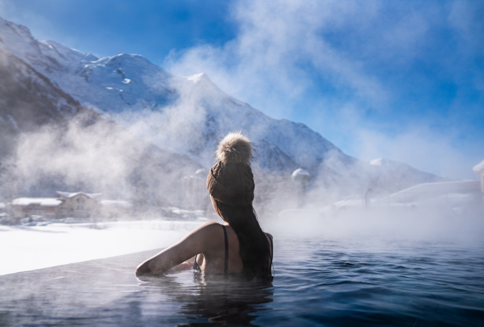 Woman looking out from the outdoor heated pool in QC Terme Spa in Chamonix, with mountain views