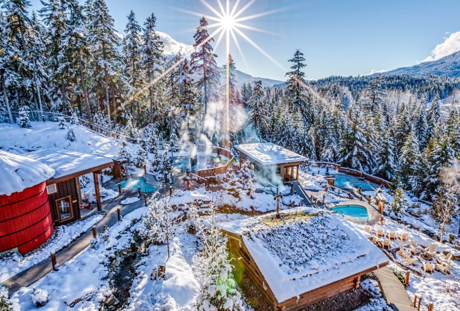 Scandinave Spa in Whistler, surrounded by snowy trees and mountains with many pools to enjoy on your luxury wellness holiday