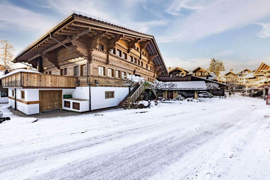 Exterior photo of Ultima Gstaad Promenade, showcasing typical white and wooden cladding. Sleeping 16-20 guests with an extensive array of facilities, it's perfect for luxury ski holidays in Gstaad!