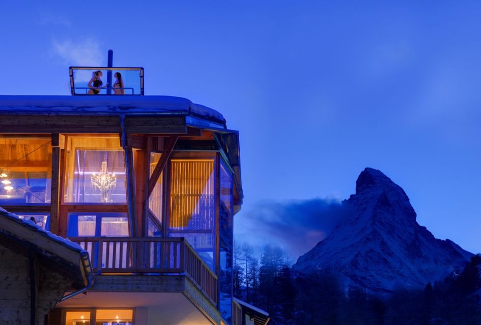 Matterhorn to the right of Backstage Chalet in Zermatt. Two people can be seen in the rising rooftop hot tub on the roof of the chalet.