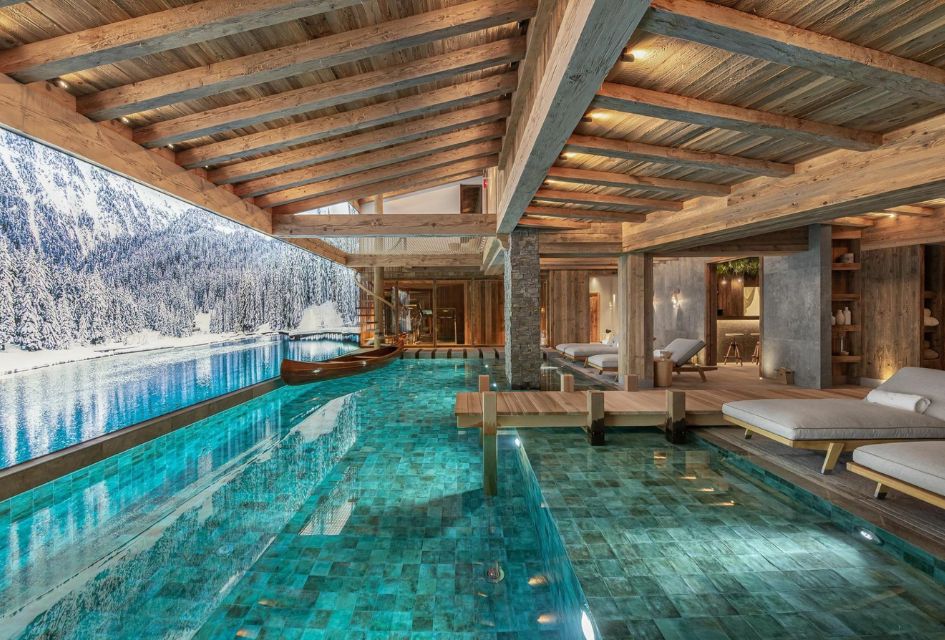 Large swimming pool of Chalet Bruxellois, complete with a small boat and a dock, and wide screen snowy views.