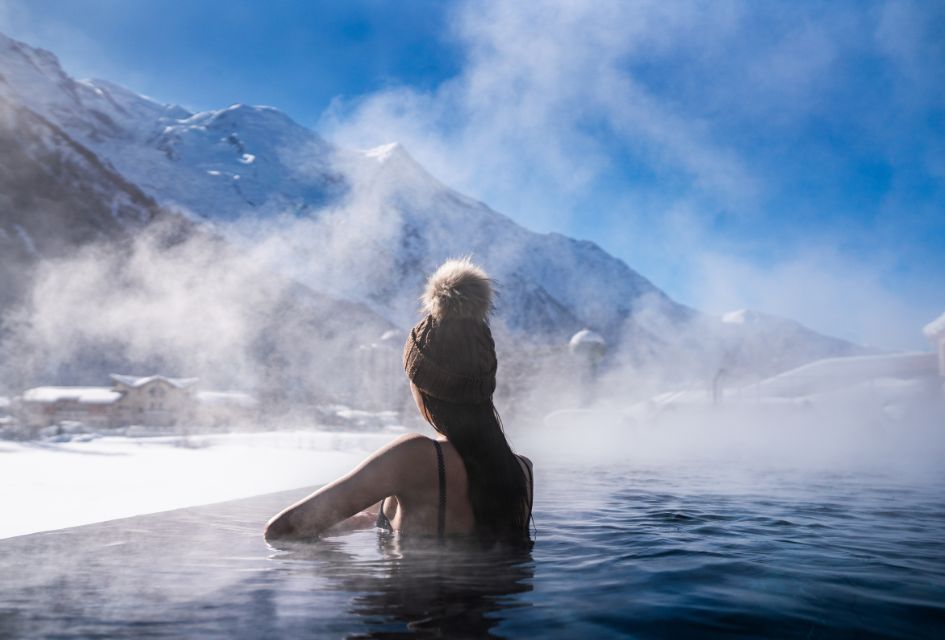 Woman looking out from the outdoor heated pool in QC Terme Spa in Chamonix, with mountain views.